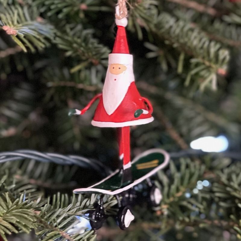 Handmade tin Santa on Skateboard Christmas ornament with a sack of gifts, designed in Denmark and handcrafted in the Philippines.
