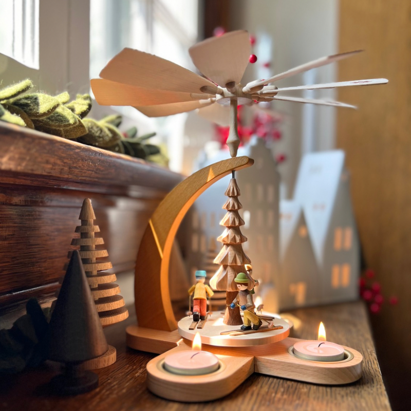 Handcrafted Richard Glässer German Christmas pyramid featuring children skiing through a snowy winter landscape, made in Seiffen, Germany.