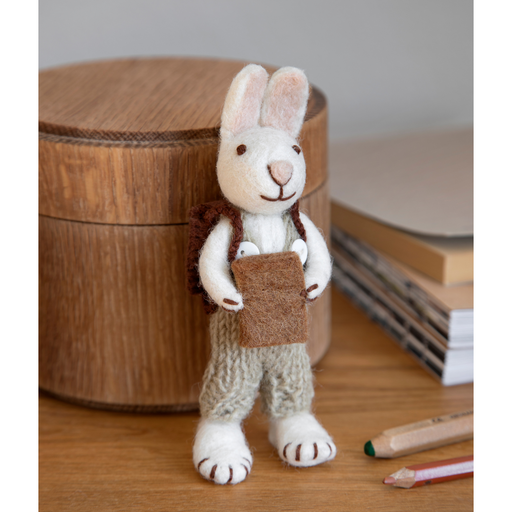 Gingerbread World European Easter Market - White Bunny figure with backpack and book 21313 shown on desk with office supplies