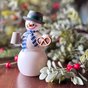 Handcrafted Seiffener Volkskunst Bavarian snowman incense smoker holding a pretzel and bierstein, wearing a blue-and-white scarf and black top hat, made in Seiffen, Germany.