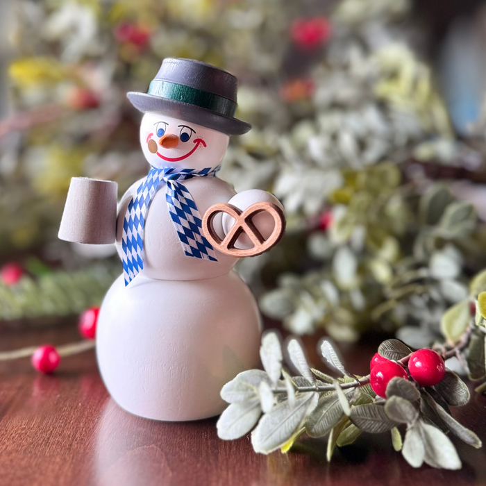 Handcrafted Seiffener Volkskunst Bavarian snowman incense smoker holding a pretzel and bierstein, wearing a blue-and-white scarf and black top hat, made in Seiffen, Germany.