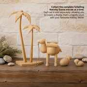 Handcrafted Emil Schalling wooden camel, palm trees and sheep from the Seiffener Volkskunst Nativity Scene collection displayed on a rustic wooden mantel with smooth natural stones and a light brick fireplace backdrop.