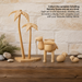 Handcrafted Emil Schalling wooden camel, palm trees and sheep from the Seiffener Volkskunst Nativity Scene collection displayed on a rustic wooden mantel with smooth natural stones and a light brick fireplace backdrop.
