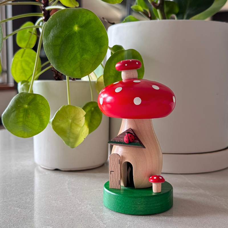 Handcrafted Richard Glässer German toadstool house incense smoker with a red mushroom roof, crooked chimney and ladybug, made in Seiffen, Germany.